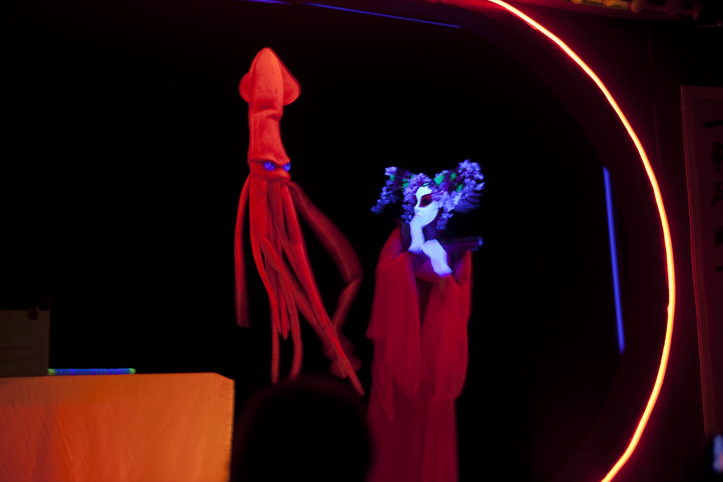 Blacklight theater scene with a glowing red squid puppet from Magical Ocean